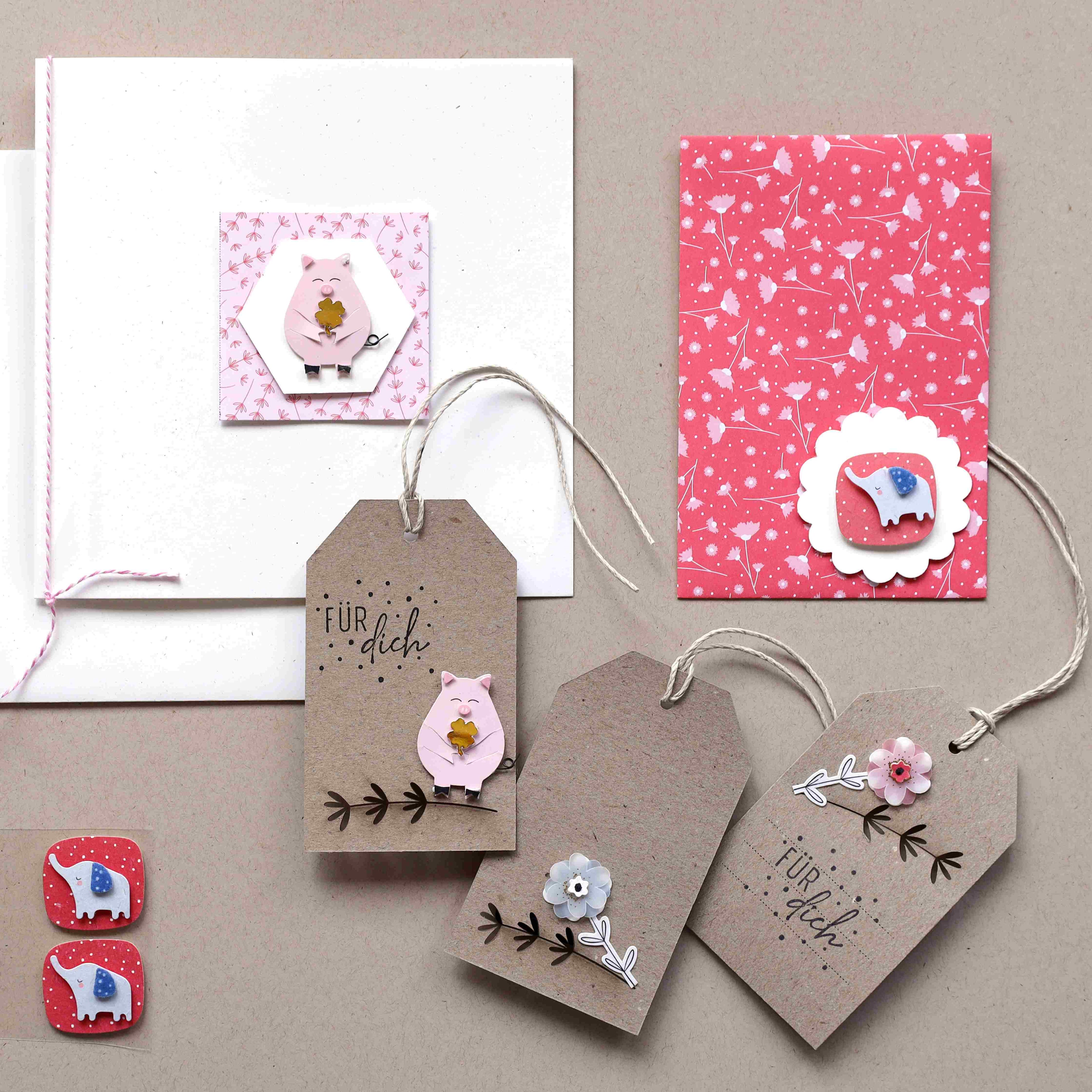 Handgefertigte Geschenkanhänger und -karten, verziert mit Tieraufklebern, Blumen und dem deutschen Text Für dich, arrangiert auf einem neutralen Hintergrund mit rot und weiß gemustertem Papier.