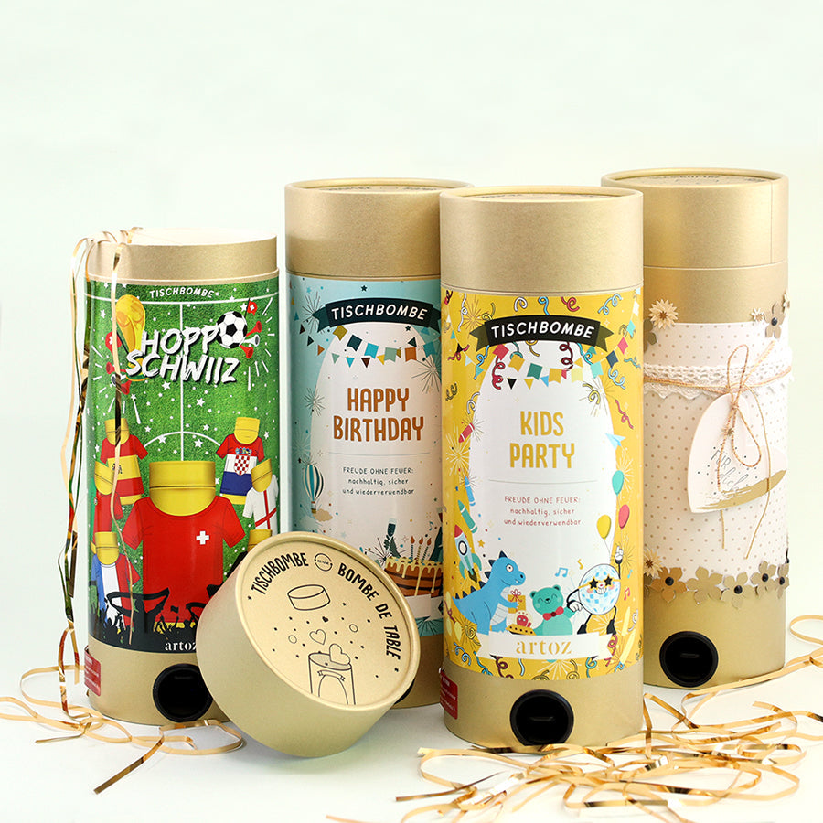 Drei farbenfrohe Happy-Birthday-Party-Popper mit festlichen Motiven und goldenen Deckeln, die aufrecht auf einer weißen Fläche stehen und von gekräuselten Bändern umgeben sind.