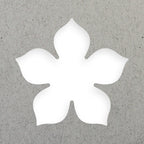 Die Artoz Papier AG Stanzer M Blume erzeugt eine fünfblättrige weiße Kirschblüte auf einem strukturierten grauen Hintergrund, ideal für Karten- oder Bastelprojekte.