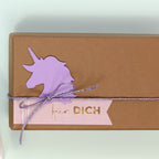Une boîte cadeau marron est ornée d'une licorne violette découpée à l'aide de l'Artoz Papier AG Stanzer M Einhorn, ainsi que d'une étiquette rose "für DICH" en or et d'une ficelle violette scintillante - un choix idéal pour les fans de Basteln.
