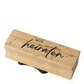 Der Stempel "wir heiraten" von Artoz Papier AG mit schwarzer Schrift ist ideal für Hochzeitsbastelarbeiten und liegt auf weißem Hintergrund.