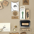Ein flaches Layout von Briefpapier für Bastelarbeiten mit dem Artoz Papier AG Stempel Menu, botanische und Haus Holzstempel Einladung, grünes Wachssiegel Set, Pilz Kissen Box, und eine Lavendel gebundene Namenskarte.
