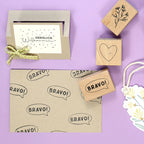 Der Artoz Papier AG Stempel Herzlich Willkommen, Grußkarte, Umschlag und Verzierungen auf Lavendel. Der Stempel hat ein fröhliches Design, das Ihren Bastelarbeiten Charme und Kreativität verleiht.