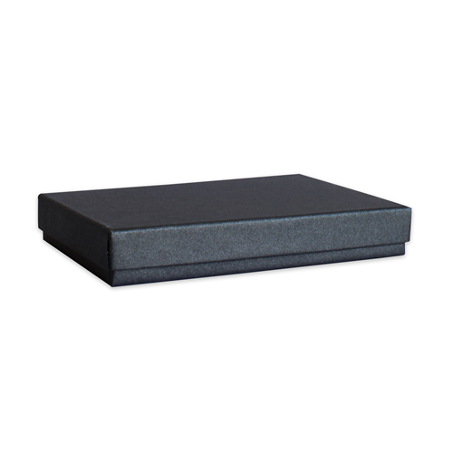 Une boîte rectangulaire fermée, d'un noir élégant et à la surface subtilement texturée — la « Geschenk-Box Pure A4 in Schwarz » d'Artoz Papier AG — repose sur un fond clair et uni, se présentant comme un emballage raffiné et une boîte-cadeau parfaite.