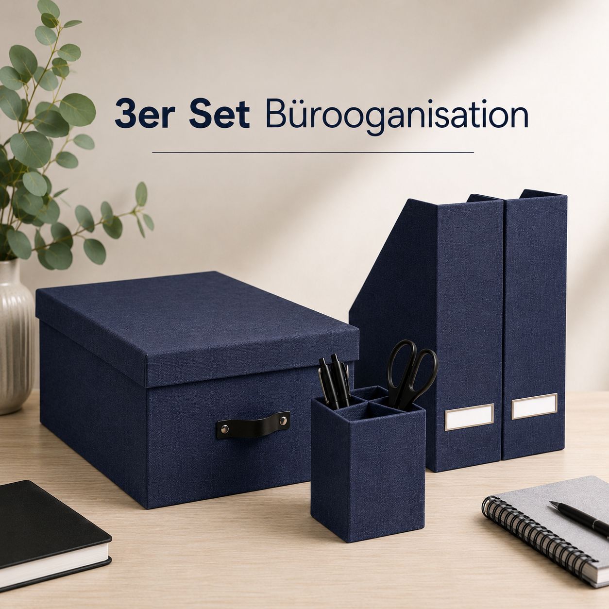 Lot de 3 articles de rangement de bureau avec boîte de rangement d'Artoz Papier AG, couleur bleu marine : pour un rangement optimal au bureau, ce lot comprend une boîte de rangement pratique, deux porte-revues élégants ainsi qu'un porte-crayons contenant des ciseaux et des stylos. Le tout est disposé de manière décorative sur un bureau, avec des carnets et une plante. Texte en haut : Lot de 3 articles d'organisation de bureau avec boîte de rangement – Artoz Papier AG.