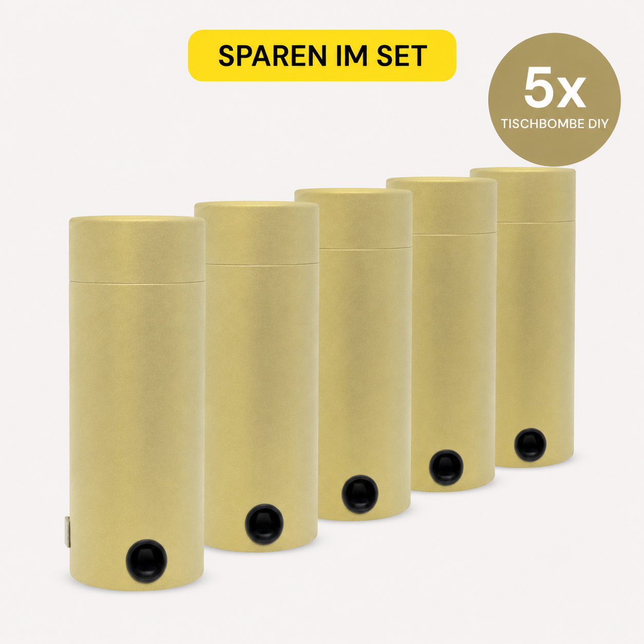 Fünf goldene, zylindrische Tischbomben ohne Feuer - "DIY" 5er Set Behälter der Artoz Papier AG, jeweils mit einem schwarzen Knopf, sind in einer Reihe angeordnet. Darüber befindet sich ein gelbes Etikett "SPAREN IM SET" und ein Kreis mit der Aufschrift "5x TISCHBOMBE DIY" auf weißem Grund.