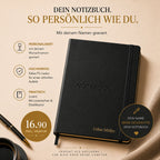 Ein schwarzes Notizbuch im A5-Format von Artoz Papier AG, graviert mit deinem Namen, dem Schriftzug „NOTEBOOK“ auf dem Einband und „Lukas Müller“ am unteren Rand – präsentiert zusammen mit einem Stift, einer Kaffeetasse und goldenen Büroklammern. Personalisierbar und preislich attraktiv.