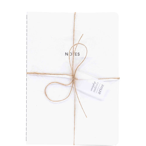 Un Notizheft A5 blanc d'Artoz Papier AG, avec la mention NOTES sur la couverture, attaché avec de la ficelle marron et une étiquette "atticz". Idéal pour un set élégant de 40 Blatt A5 Notizheft.