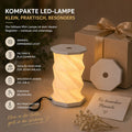 La lampe de table LED compacte Minora d'Artoz Papier AG est pliable, dotée d'un variateur tactile, rechargeable via USB-C, facile à utiliser et constitue une excellente idée de cadeau. Le texte en allemand met en avant ses avantages. Des icônes illustrent sa mobilité et sa facilité d'utilisation.