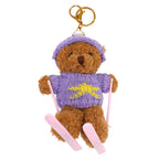 Wir stellen vor: den „Ski-Teddy“-Anhänger – Plüschbär mit Skiern von Artoz Papier AG: Dieser braune Teddybär-Schlüsselanhänger trägt eine lila Mütze und einen Pullover mit gelbem Stern und hält rosa Skistöcke sowie dazu passende rosa Skier in den Händen. Ideal als niedlicher Geschenkanhänger oder als charmantes Geschenkzubehör für jeden besonderen Anlass.