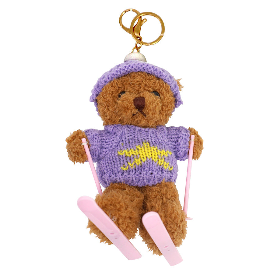 Wir stellen vor: den „Ski-Teddy“-Anhänger – Plüschbär mit Skiern von Artoz Papier AG: Dieser braune Teddybär-Schlüsselanhänger trägt eine lila Mütze und einen Pullover mit gelbem Stern und hält rosa Skistöcke sowie dazu passende rosa Skier in den Händen. Ideal als niedlicher Geschenkanhänger oder als charmantes Geschenkzubehör für jeden besonderen Anlass.