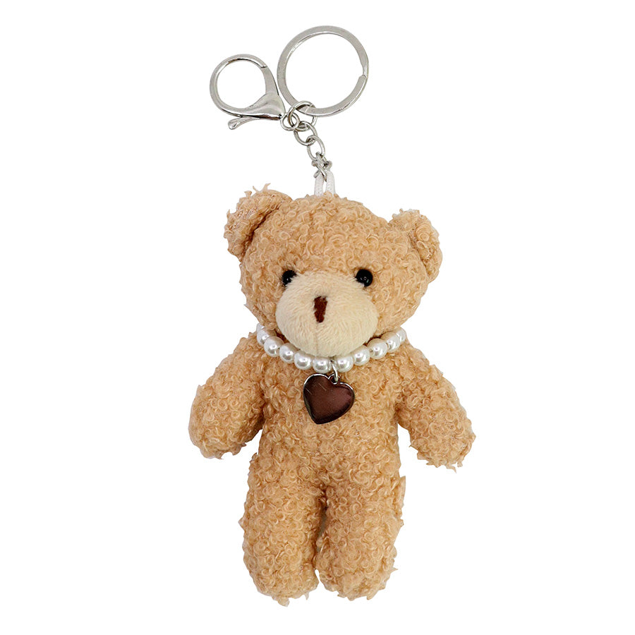Entdecken Sie den „Teddy-Anhänger – Plüschbär mit Herzkette“ von Artoz Papier AG: ein kleiner, lockiger brauner Plüschbär als Schlüsselanhänger, verziert mit einer Perlenkette und einem Herzanhänger – eine entzückende Wahl als Wintergeschenk oder für den täglichen Gebrauch als Schlüsselanhänger.