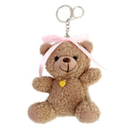 Découvrez l'adorable « porte-clés ours en peluche – ours en peluche avec nœud dans les cheveux » d’Artoz Papier AG, un ours en peluche en forme de porte-clés orné d’un nœud rose sur la tête et d’un minuscule pendentif en forme de cœur doré – une idée de cadeau idéale et pleine de tendresse.