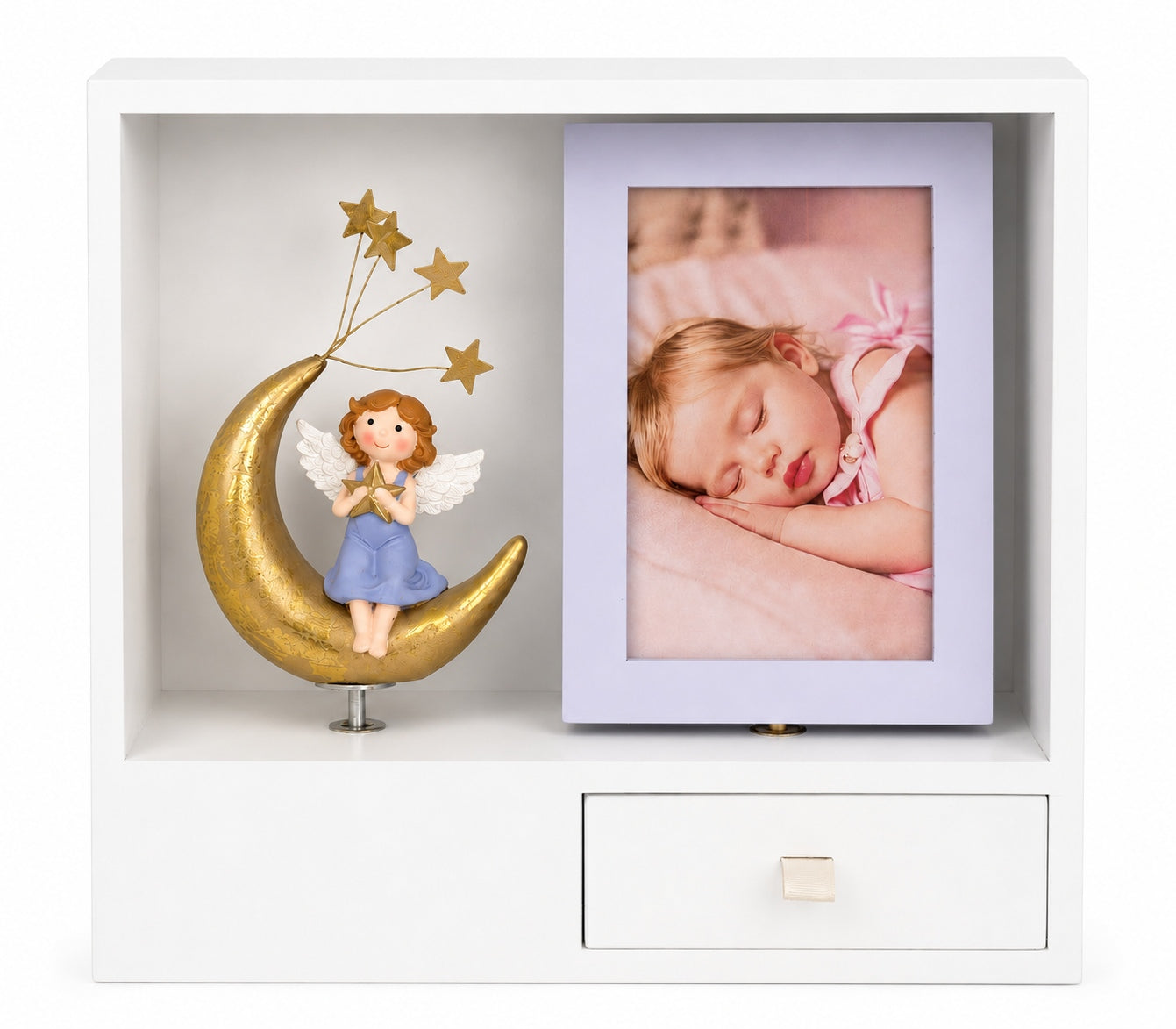 Auf einem weißen Regal kommt die Dekoration „Geburt Mädchen“ von Artoz Papier AG wunderschön zur Geltung – sie zeigt einen goldenen Halbmond mit einem zierlichen Engel, der Sterne hält, sowie ein gerahmtes Foto eines schlafenden Babys, das in rosa Bettwäsche eingebettet ist. Mit seiner kleinen Schublade unten, die für zusätzliche Funktionalität sorgt, vereint dieses sentimentale Stück Charme und Zweckmäßigkeit und eignet sich somit perfekt für maßgeschneiderte Lösungen in jedem Kinderzimmer.