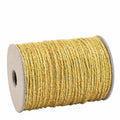 Eine 20-Meter-Spule Geschenkband Gelb der Artoz Papier AG mit goldglänzender Jute-Polyester-Geflechtkordel, die sauber auf eine Pappspule mit hohlem Kern gewickelt ist, wird vor einem weißen Hintergrund gezeigt.