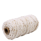 Une bobine de 25 m de Geschenkband Natur - Gold d'Artoz Papier AG : une épaisse ficelle de coton blanc avec des fils de Lurex dorés, enroulée autour d'une âme en carton et présentée sur un fond blanc.