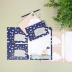 Le kit d'écriture pour enfants « Pirates » d'Artoz Papier AG comprend des enveloppes bleues ornées d'un motif de bateau pirate, un classeur assorti, des motifs représentant des nuages, un stylo et du papier rose – idéal comme papier à lettres pour les enfants.
