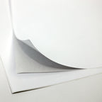 Gros plan sur une pile d'Artoz Papier AG A4 Klebefolie zum selber bedrucken - für Tischbombe DIY, la feuille supérieure étant partiellement soulevée pour révéler les couches inférieures, sur un fond blanc uni.