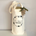 Un sac cadeau en tissu couleur crème de la société Artoz Papier AG, orné du motif « Von Herzen für Dich » (Du fond du cœur, pour toi), est décoré de cœurs noirs et d'un texte en allemand ; fermé par un ruban vert et des étiquettes, il se détache nettement sur le fond clair – un emballage écologique, idéal pour présenter du vin avec élégance.