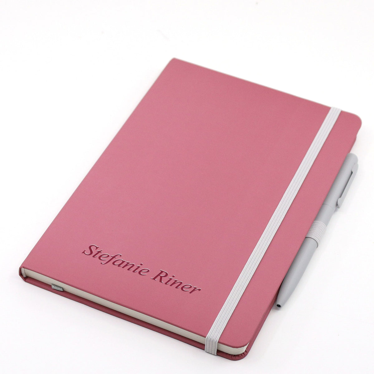 Un carnet au format A5 avec stylo, dans une élégante teinte bordeaux, signé Artoz Papier AG, qui peut être personnalisé avec votre nom ou le texte de votre choix sur la couverture. Le carnet se ferme en toute sécurité grâce à un élastique blanc et le stylo à bille gris est fixé de manière pratique sur le côté droit.