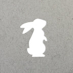 La silhouette blanche d'un lapin assis, inspirée du Stanzer S Hase d'Artoz Papier AG, est centrée sur un fond texturé gris clair.