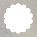 Un cercle blanc festonné, réalisé avec le Artoz Papier AG Stanzer M Wellen-Kreis, est centré sur un fond texturé gris clair ressemblant à du Bastelpapier ou à du carton.
