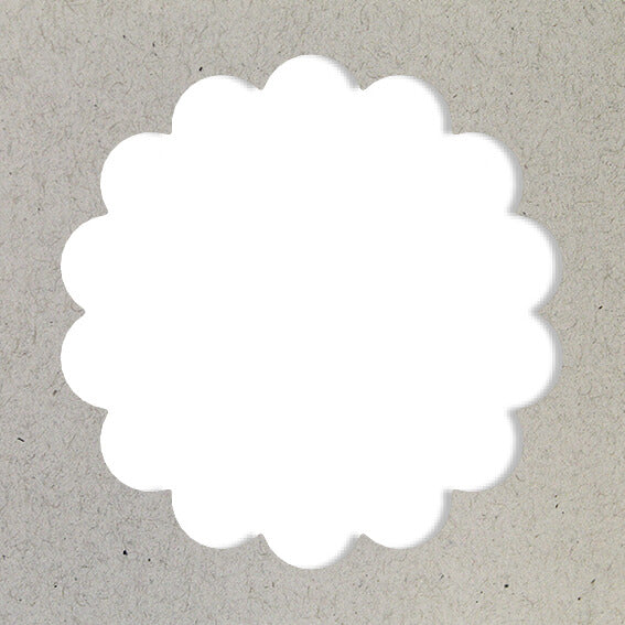Un cercle blanc festonné, réalisé avec le Artoz Papier AG Stanzer M Wellen-Kreis, est centré sur un fond texturé gris clair ressemblant à du Bastelpapier ou à du carton.