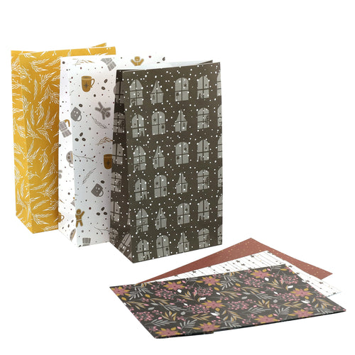 Six sacs-cadeaux décoratifs issus du « lot de 6 sacs en papier au motif hivernal, en différentes couleurs » de la société Artoz Papier AG, fabriqués à partir de papier certifié FSC et ornés de différents motifs dans les tons jaune, blanc et vert foncé, sont posés debout. Devant celles-ci se trouvent trois feuilles de papier de soie à motifs assorties.