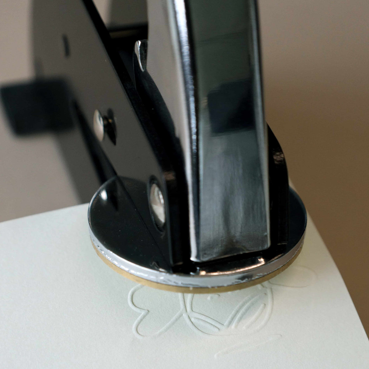 Gros plan sur un outil d'estampage « Prägestempel Ersatz Sujet Engel » de la marque Artoz Papier AG, en train d'imprimer un motif d'ange en relief sur une feuille de papier blanc. Le motif estampé partiellement visible sous l'outil met en évidence son adéquation aux projets de bricolage et aux finitions décoratives complexes.