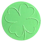 Un objet circulaire vert sur lequel figure, au centre, le contour d'un trèfle à quatre feuilles, rappelant le motif « Prägestempel Ersatz Sujet Kleeblatt » créé par Artoz Papier AG.