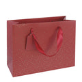 Mais bien sûr ! Voici votre phrase reformulée en utilisant les données produit indiquées : Le sac cadeau « Pure M » d’Artoz Papier AG, dans des tons rouge et or de Noël, séduit par son design festif rouge rehaussé d’élégantes touches dorées, ses poignées en ruban résistantes et son étiquette cadeau vierge déjà fixée – idéale comme sac en papier kraft raffiné ou comme emballage cadeau pratique pour toutes les occasions spéciales. Sur fond blanc, elle apporte une touche d’élégance à vos cadeaux.