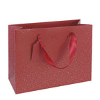 Mais bien sûr ! Voici votre phrase reformulée en utilisant les données produit indiquées : Le sac cadeau « Pure M » d’Artoz Papier AG, dans des tons rouge et or de Noël, séduit par son design festif rouge rehaussé d’élégantes touches dorées, ses poignées en ruban résistantes et son étiquette cadeau vierge déjà fixée – idéale comme sac en papier kraft raffiné ou comme emballage cadeau pratique pour toutes les occasions spéciales. Sur fond blanc, elle apporte une touche d’élégance à vos cadeaux.
