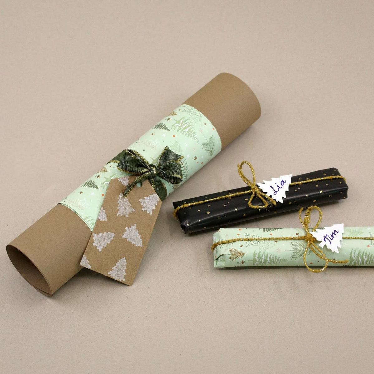 Eine braune Papierrolle mit grüner Verpackung, verziert mit einer Schleife und einem baumförmigen Anhänger, der mit dem Stempel „Tannenbaum klein“ von Artoz Papier AG gestaltet wurde, liegt neben zwei Geschenken, die mit den Namen „Lila“ und „Tim“ beschriftet und mit goldenen Schnurschleifen verziert sind – alles auf einer beigen Unterlage arrangiert: die perfekte Inspiration für DIY-Bastelprojekte mit wunderschönen Akzenten, die mit dem Stempel „Holz“ gestaltet wurden.
