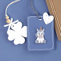 La présentation à plat montre une étiquette cadeau blanche en forme de trèfle avec des perles en bois et un nœud, un autocollant Artoz 3D Sticker "Einhorn" blau by Artoz Papier AG, et une enveloppe marron décorée d'un accent en papier en forme de cœur.