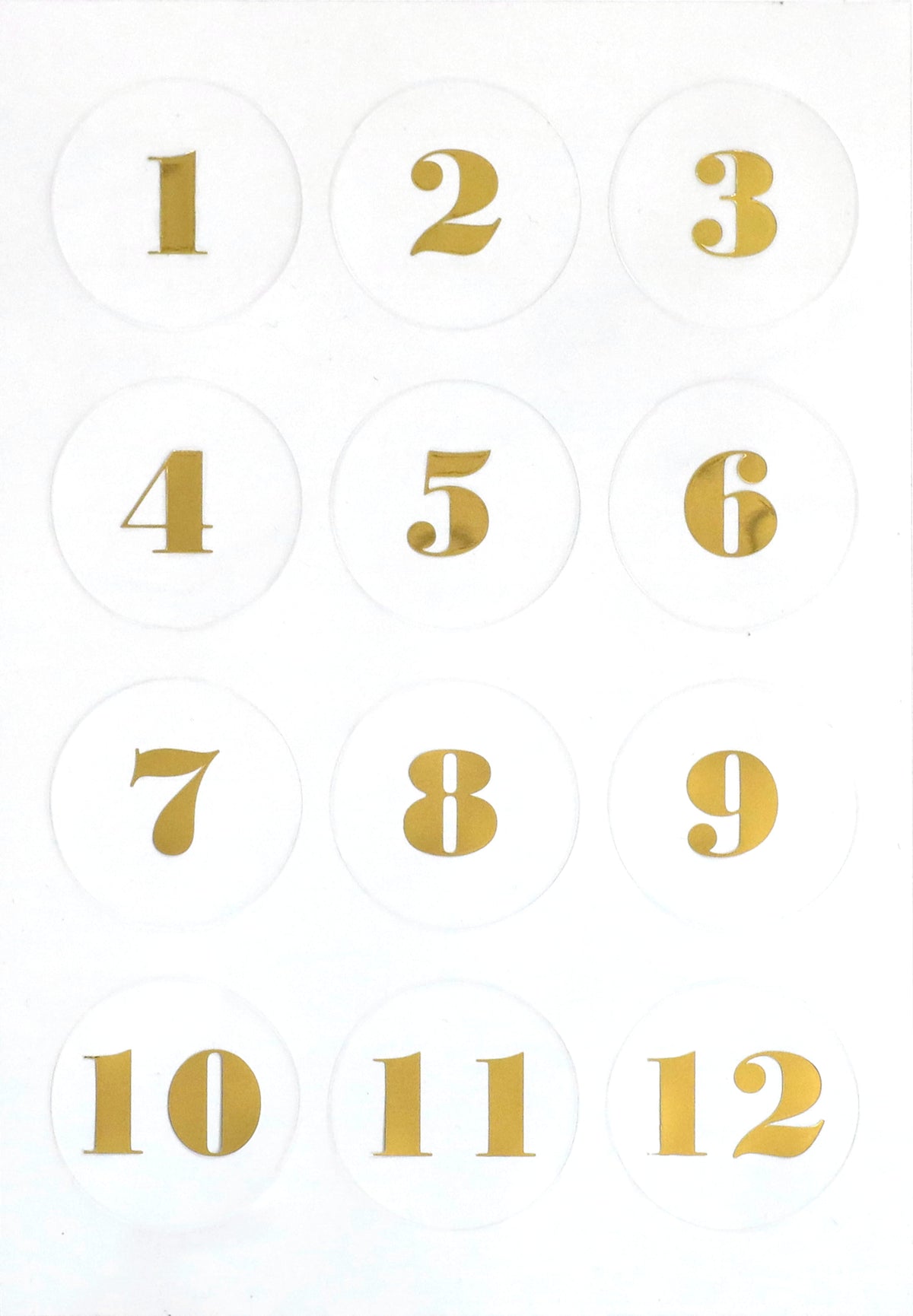 Douze cercles blancs comportant les chiffres dorés de 1 à 12, disposés en grille 3x4 sur fond blanc — parfaits pour les projets d'Avent ou comme matériel de loisirs créatifs, grâce aux autocollants transparents « Artoz Sticker Advent » d'Artoz Papier AG.