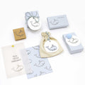 Un charmant coffret cadeau d'Artoz Papier AG comprenant des boîtes, une pochette à cordon et des cartes avec un adorable motif de baleine. Comprend le tampon Stempel Wal et une carte avec "MEIN ERSTER HAARSCHNITT" en allemand sur fond blanc.