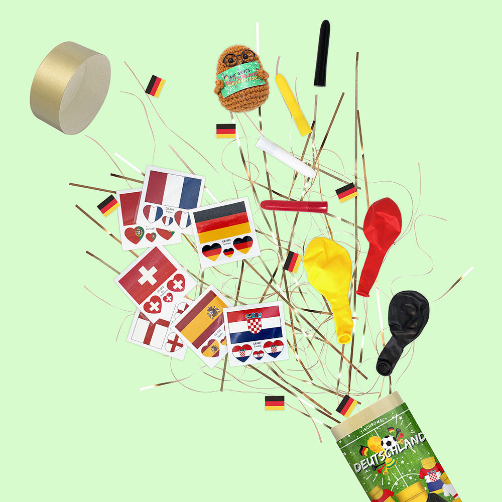Des décorations de fête colorées, des ballons et des petits drapeaux européens sont éparpillés sur un fond vert clair, jaillissant de l'Artoz Papier AG "Tischbombe ohne Feuer - Fussball WM Team Deutschland" pour encourager l'équipe d'Allemagne.