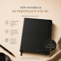 Ein schwarzes "A5 Notizbuch mit deinem Namen graviert" von Artoz Papier AG, mit NOTEBOOK-Prägung und Lukas Müller am unteren Rand, liegt auf beigem Untergrund neben Goldstift, Büroklammern und einem schwarzen Label für das personalisierte Notizbuch.
