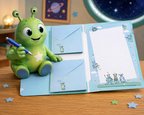 Un adorable extraterrestre vert tient un stylo à côté d'enveloppes bleues pour enfants « Briefumschläge Kinder » et du kit d'écriture pour enfants « Aliens » d'Artoz Papier AG, comprenant des motifs d'extraterrestres, des enveloppes et du papier ligné, le tout posé sur un bureau avec un fond représentant un espace étoilé.